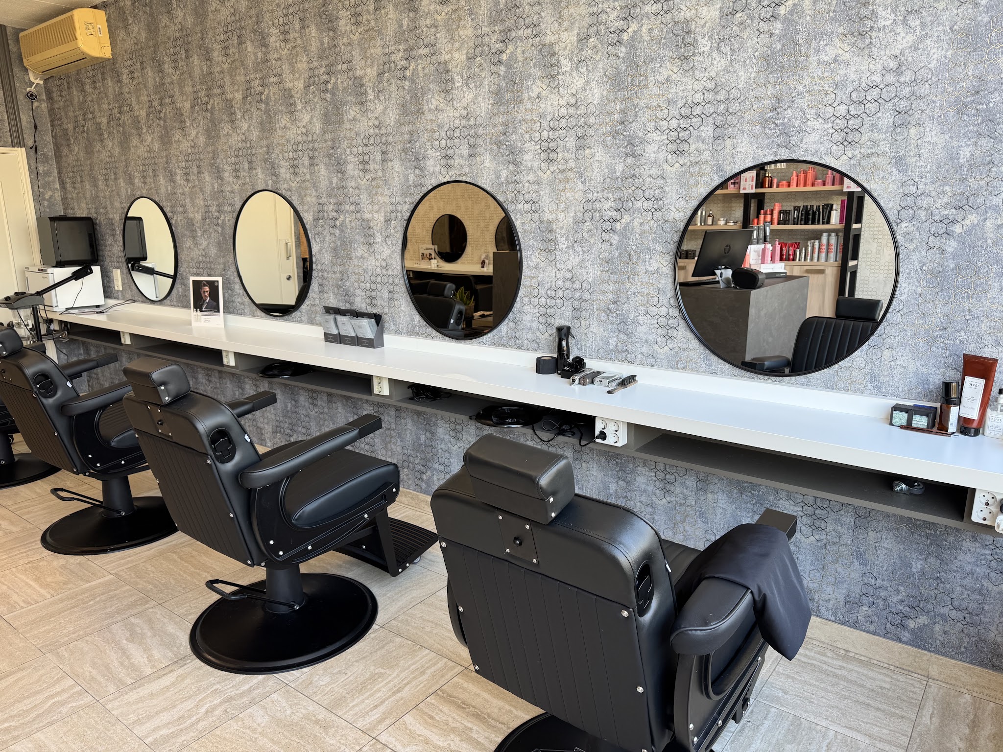De salon: een rij zwarte stoelen voor ronde spiegels op een visgraatvloer