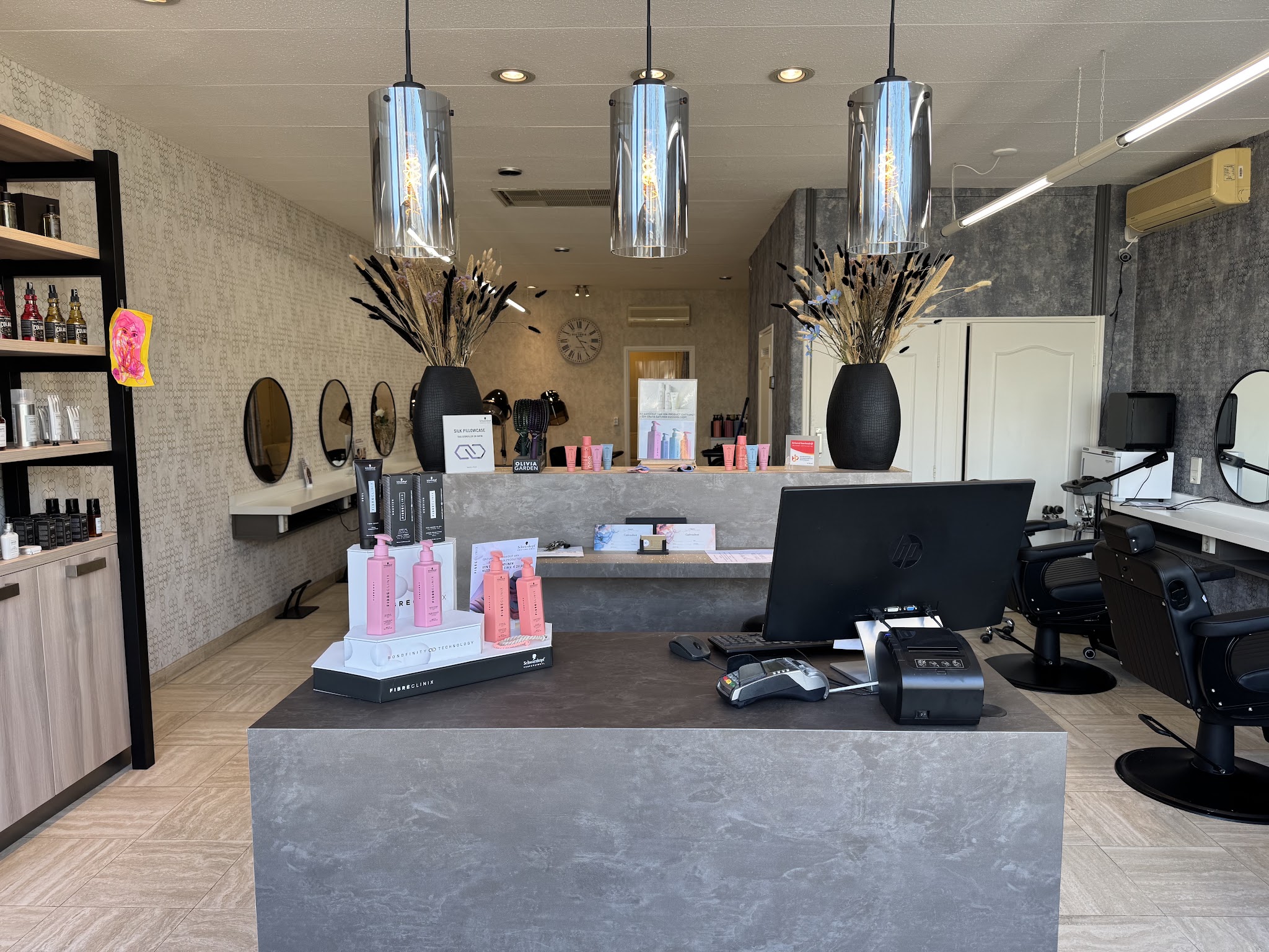 De balie van de salon met hanglampen, producten en ronde spiegels