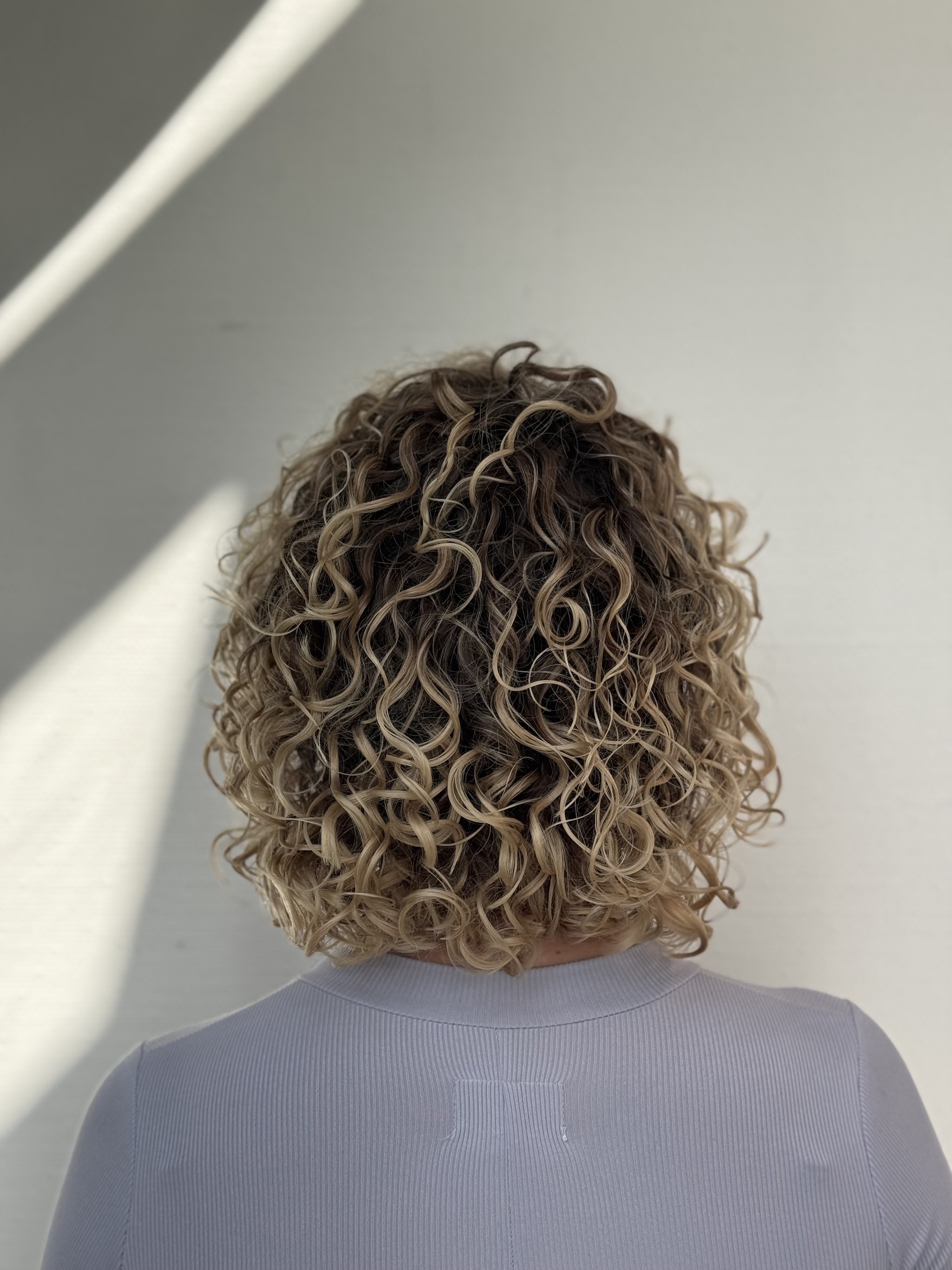 Blonde, gedefinieerde krullen na een Curly Cut, gezien vanaf de rug