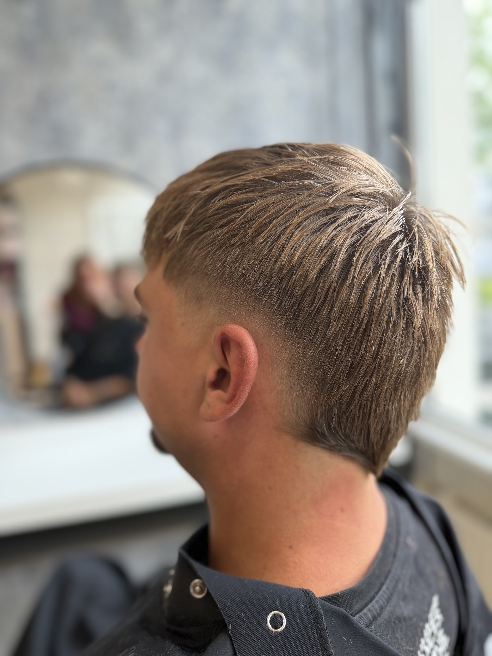 Herenkapsel met textuur bovenop en een strakke skin fade, gezien vanaf de zijkant