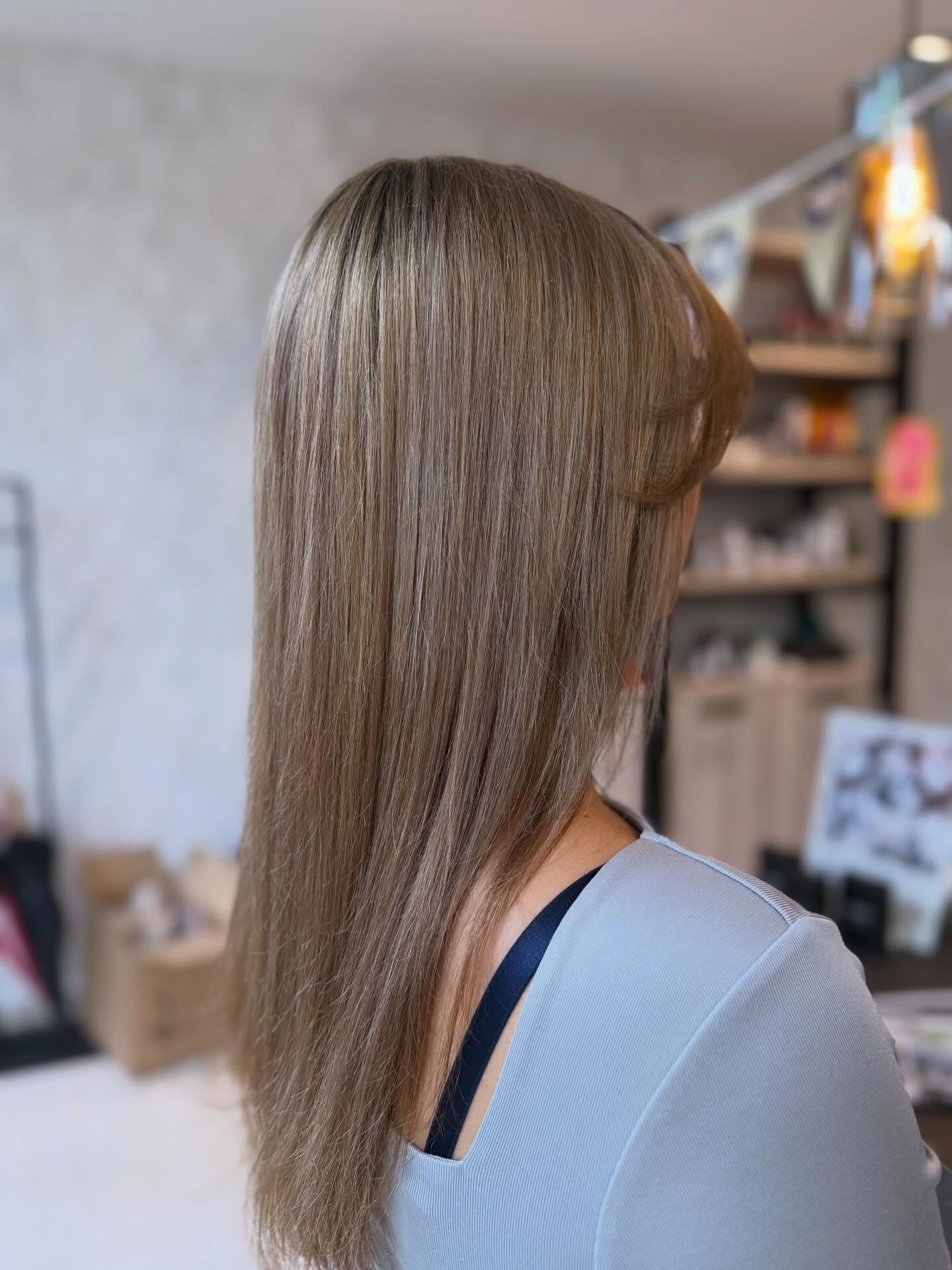Lang asblond haar, strak gestyled, gezien vanaf de rug